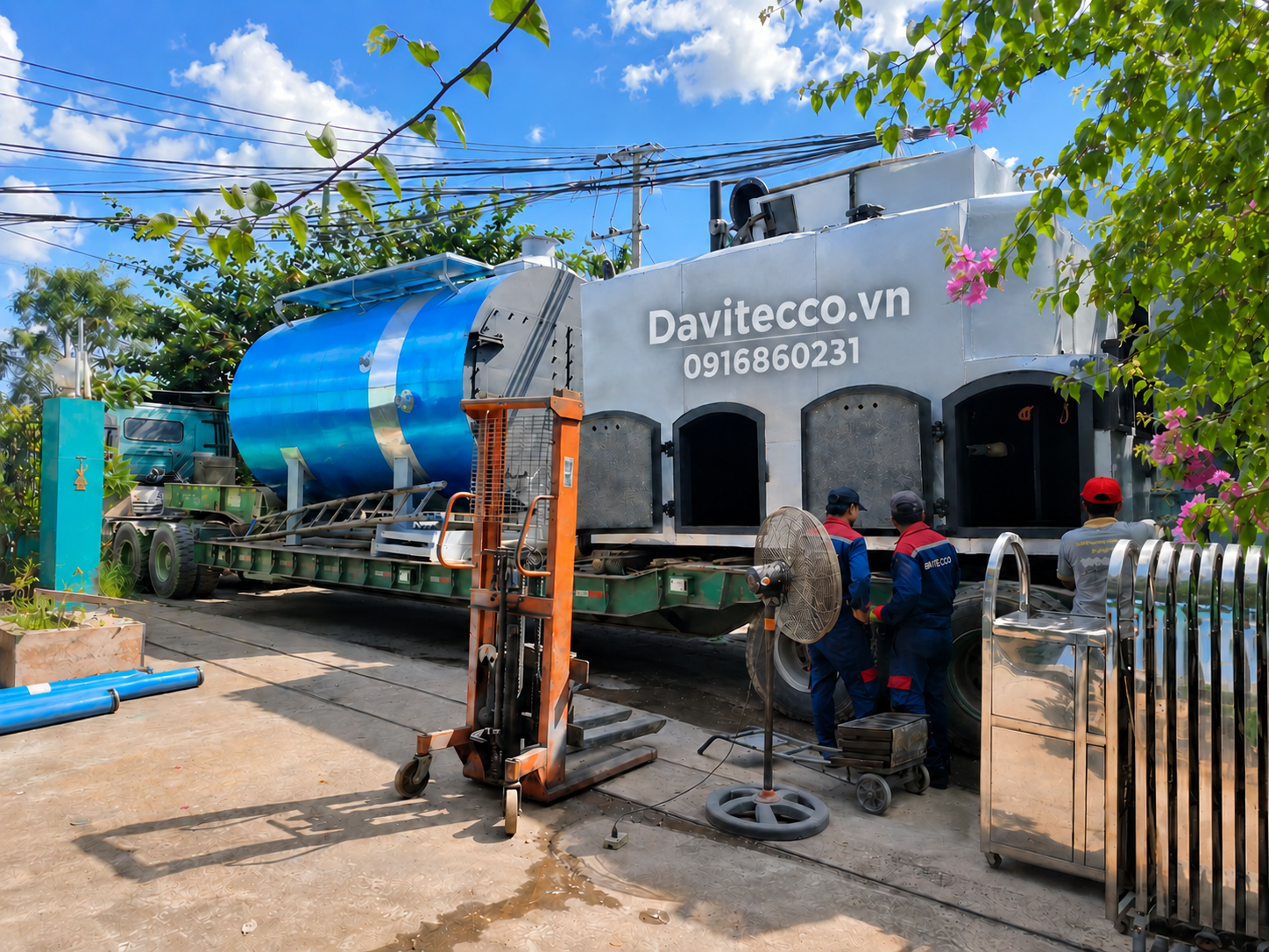 Thân lò hơi nằm ngang màu xanh và cụm buồng đốt DAVITECCO đặt trên xe vận chuyển, bên cạnh có nhân viên kỹ thuật